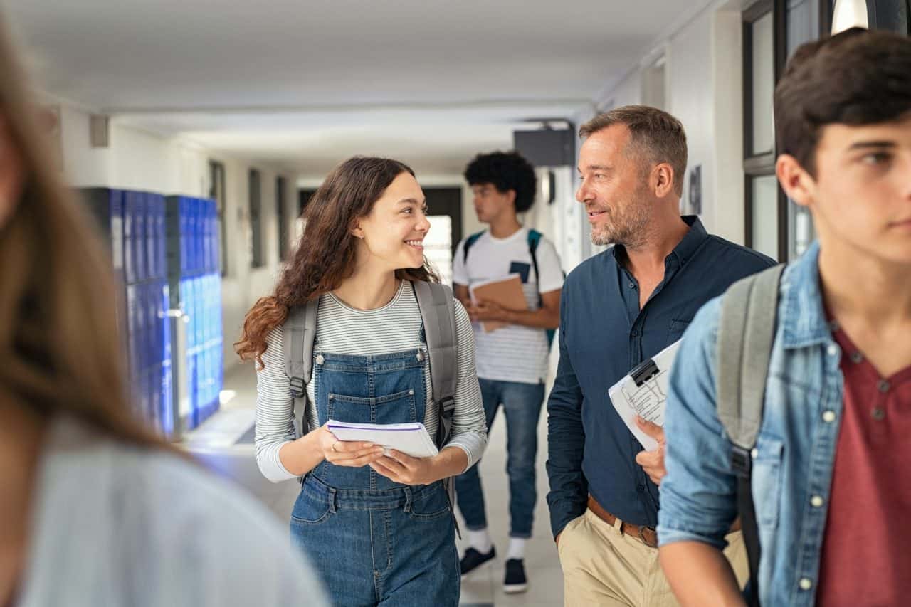 student-girl-asking-to-professor-in-college-corridor Home